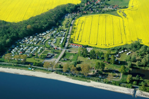 Luchtfoto van Camping Ostseequelle met glamping aan de Oostzee en gele velden in Duitsland.