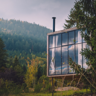 Nutchel Cabins - Tiny Houses Elzas: moderne glamping hut met glazen wand in een groene, heuvelachtige omgeving.