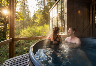 Couple enjoying a relaxing soak in an outdoor hot tub at Nutchel Cabins - Tiny Houses Elzas in the woods.