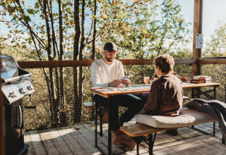 Padre e hijo juegan cartas en la terraza de Nutchel Cabins - Tiny Houses Elzas, rodeados de naturaleza.