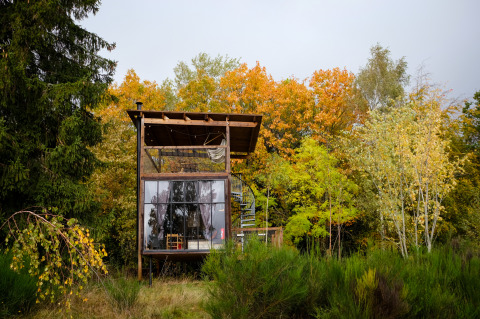 Nutchel Cabins Elzas Glamping: Modernes Tiny House mit Panoramafenstern im herbstlichen Wald gelegen.