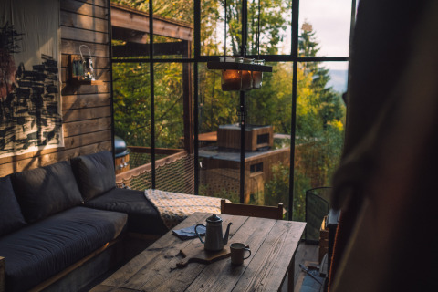 Hyggelig indretning i Nutchel Cabins - Tiny Houses Elzas med store vinduer og udsigt til grøn natur.