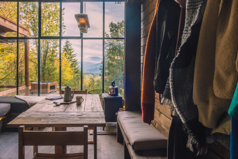 Interior de Nutchel Cabins con gran ventanal, vistas al bosque y montañas, ambiente relajado.