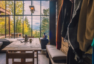 Interior de Nutchel Cabins con gran ventanal, vistas al bosque y montañas, ambiente relajado.