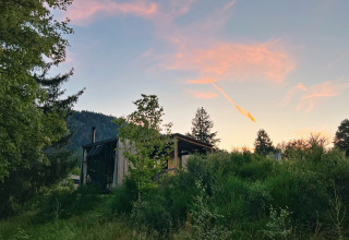 Alojamiento glamping Nutchel Cabins - Tiny Houses Elzas rodeado de naturaleza y árboles al atardecer.