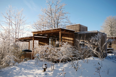 Nutchel Cabins - Tiny Houses Elzas hébergement glamping entouré d'arbres enneigés sous un ciel bleu clair.