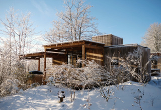 Nutchel Cabins - Tiny Houses Elzas glamping accommodation surrounded by snowy trees and clear blue sky.