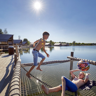 Two boys playing on a netted area over water at TerSpegelt WaterLodges glamping accommodation in Brabant.
