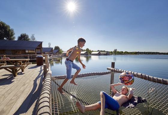 Two boys playing on a netted area over water at TerSpegelt WaterLodges glamping accommodation in Brabant.