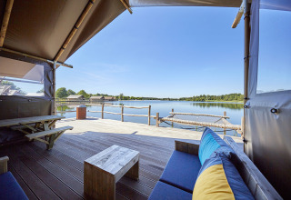 Glamping en Recreatiepark TerSpegelt WaterLodges Brabant con terraza, vistas al lago y hamaca sobre el agua.