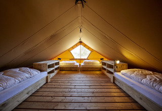 Vista interior de una tienda glamping en Recreatiepark TerSpegelt WaterLodges Brabant con cuatro camas.