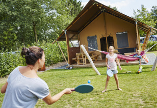 Familia juega con palas frente a tienda glamping en Recreatiepark TerSpegelt WaterLodges Brabant, Países Bajos.
