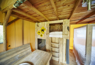 Vue intérieure du glamping au Recreatiepark TerSpegelt - WaterLodges Brabant avec lits superposés en bois.