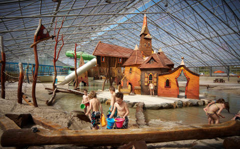 Niños juegan en un parque acuático cubierto con castillo de cuento en Recreatiepark TerSpegelt, WaterLodges Brabant.