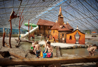 Children playing in an indoor water playground with a fairytale castle at Recreatiepark TerSpegelt, WaterLodges Brabant.