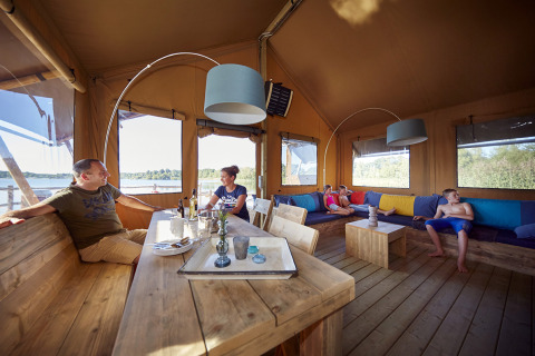 Famiglia rilassata in una WaterLodge di glamping presso Recreatiepark TerSpegelt, con vista sul lago.