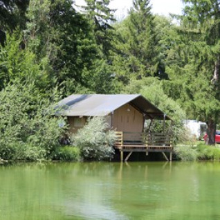Hébergement glamping au bord d’un lac entouré d’arbres au Camping Ammertal - Lodges Beieren en Bavière.