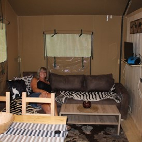 Woman relaxing on a couch in Camping Ammertal - Lodges Beieren, stylishly furnished glamping accommodation.