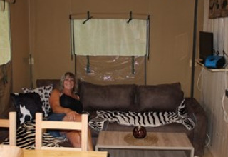 Woman relaxing on a couch in Camping Ammertal - Lodges Beieren, stylishly furnished glamping accommodation.