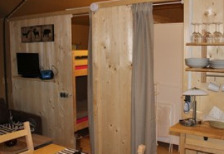 Indvendigt billede af hyggelig glampinghytte på Camping Ammertal - Lodges Beieren med træmøbler og køkken.
