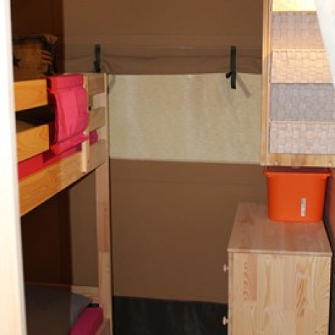 Interior of glamping tent with bunk beds, chest of drawers, and bucket at Camping Ammertal - Lodges Beieren.