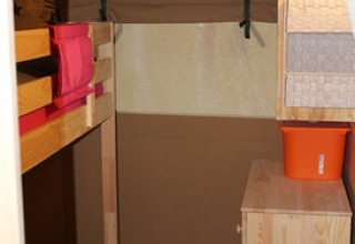 Interior of glamping tent with bunk beds, chest of drawers, and bucket at Camping Ammertal - Lodges Beieren.