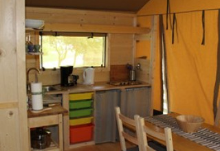 Interior view of Camping Ammertal - Lodges Beieren glamping accommodation with wooden furniture and kitchen area.