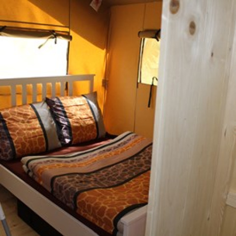 Vista interna dell'alloggio glamping presso Camping Ammertal - Lodges Beieren con letto e finestra.