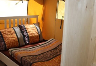 Indendørsbillede af glamping-indkvartering på Camping Ammertal - Lodges Beieren med seng og vindue.