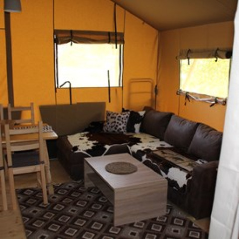Interieur van een glamping tent met bank, tafel en stoelen bij Camping Ammertal - Lodges Beieren.