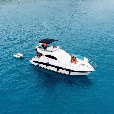 A luxury yacht with people on board floats on clear blue water near Lavita Camp Cagliari, Sardinia.