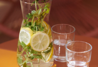 Karaffe mit Zitronen- und Kräuterwasser und zwei Gläsern, serviert bei Lavita Camp Cagliari Glamping-Zelten.