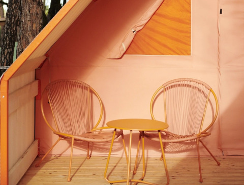 Twee moderne stoelen en een tafeltje op het houten terras bij Lavita Camp Cagliari glamping op Sardinië.
