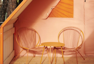 Twee trendy stoelen en een tafeltje op het houten terras van Lavita Camp Cagliari glamping op Sardinië.