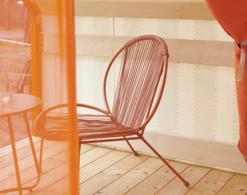 Interno della tenda glamping Lavita Camp Cagliari con sedia moderna e tavolino su terrazza in legno in Sardegna.