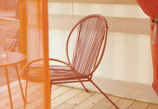 Interieur van Lavita Camp Cagliari glampingtent met designstoel en tafel op houten terras in Sardinië.