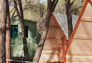 Alojamiento glamping en Lavita Camp Cagliari, Cerdeña, con tiendas y cabañas verdes entre los árboles.