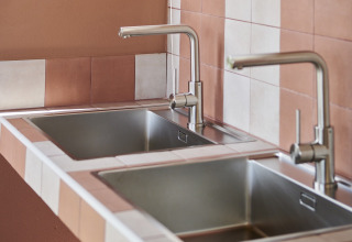 Twee roestvrijstalen spoelbakken en kranen in de gemeenschappelijke keuken van Lavita Camp Cagliari - Glampingtenten Sardinië.