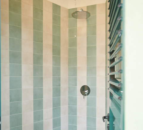 Ducha moderna con azulejos verdes y beige en Lavita Camp Cagliari, tiendas glamping en Cerdeña.