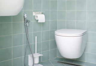 Moderne campingbadeværelse hos Lavita Camp Cagliari med væghængt toilet, bruser og toiletbørste.