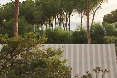 Udsigt over Lavita Camp Cagliari glampingtelt på Sardinien med træer og havet i baggrunden.