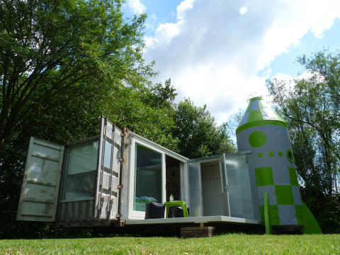 Glamping unico nel sud dell’Olanda con abitazione container e struttura a forma di razzo nel verde.