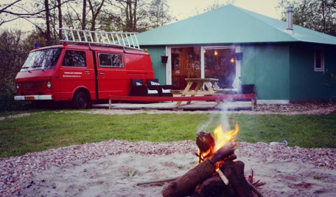 Einzigartige Glamping-Unterkunft bei De Vreemde Vogel in Zuid-Holland mit rotem Van, Hütte und Lagerfeuer.