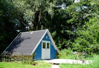 Piccola casetta blu a forma di A per glamping con terrazza immersa nel verde a De Vreemde Vogel, Zuid-Holland.