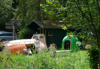 Kinderen spelen bij unieke glampingaccommodaties van De Vreemde Vogel, omgeven door groen in Zuid-Holland.