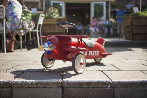 Avión de pedales rojo 'Red Flyer' en el exterior en De Vreemde Vogel, un glamping único en Zuid-Holland.