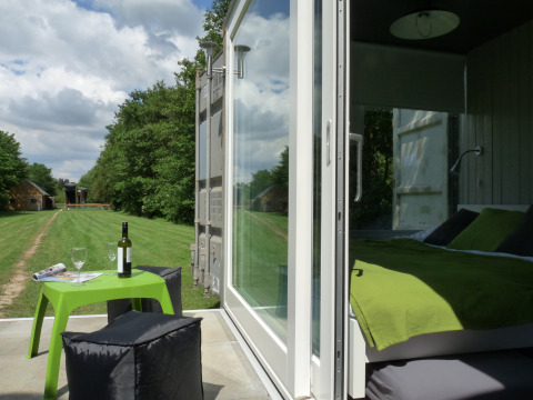 Hébergement glamping à De Vreemde Vogel avec lit vert moderne et espace extérieur convivial en pleine nature.