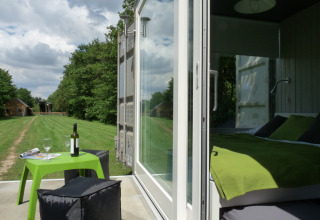 Hébergement glamping à De Vreemde Vogel avec lit vert moderne et espace extérieur convivial en pleine nature.