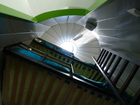 Interior of glamping accommodation with bunk beds and round skylight, De Vreemde Vogel, South Holland.