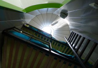 Interieur van glampingaccommodatie met stapelbedden en rond dakraam, De Vreemde Vogel, Zuid-Holland.